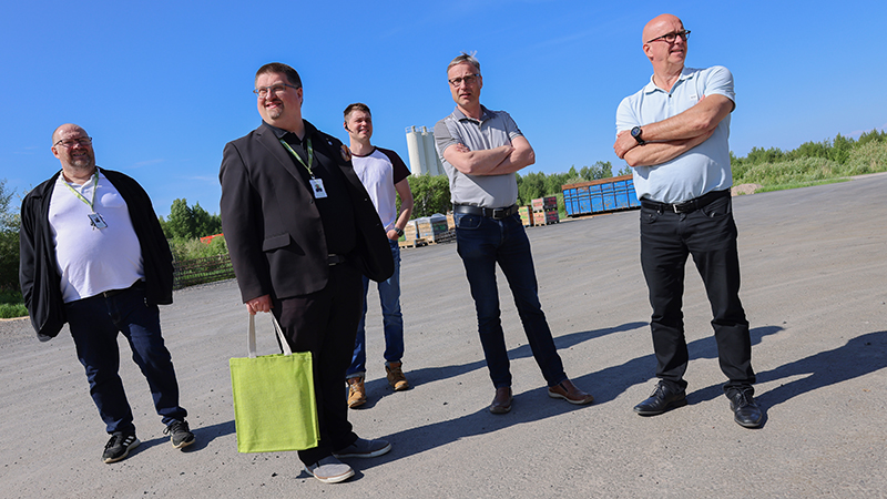 Miesporukka seisoo yritystontilla.