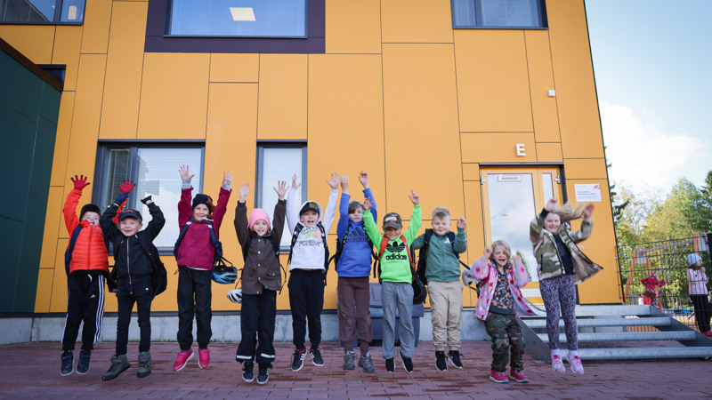 Lapset hyppäävät ilmaan koulun pihalla