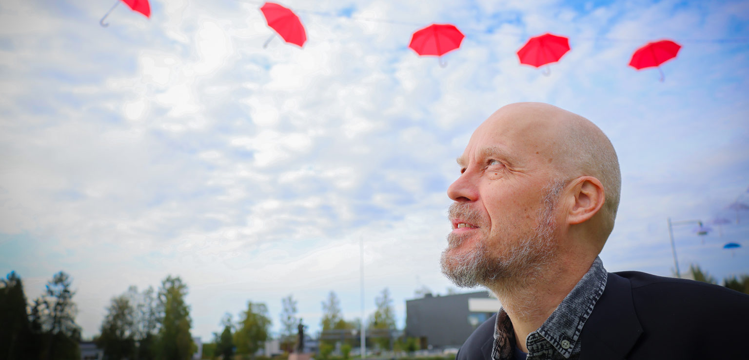 Kirjasto- ja kulttuurijohtaja Janne Nevala seisoo Liminganraitilla LimmiFestiä koristavien punaisten sateenvarjojen alla.