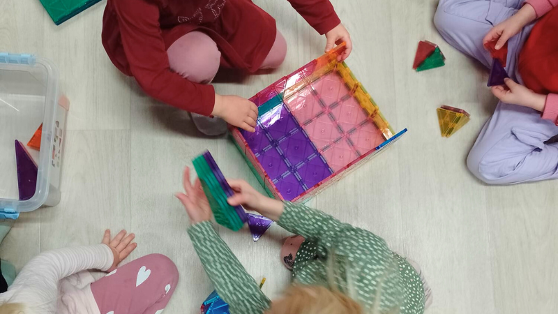 Neljä lasta leikkimässä värikkäillä rakentelupalikoilla.