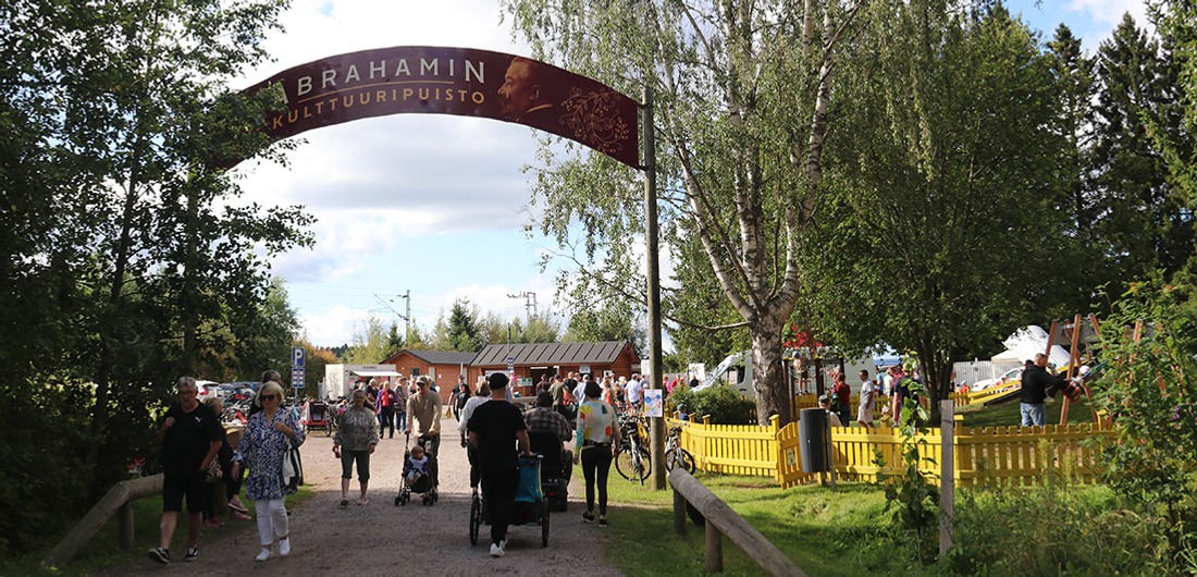 Markkinaväkeä kulkemassa Abrahamin kulttuuripuistoon kyltin alla.