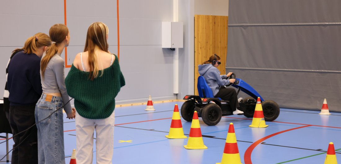 Kolme opiskelijaa ohjaamassa polkuautoilevaa nuorta radalla.