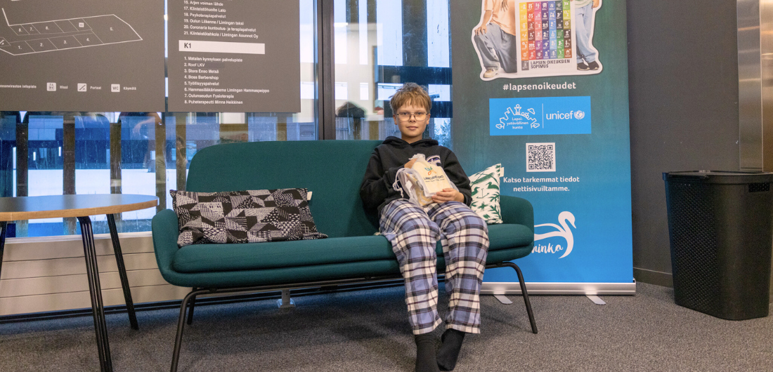 Eevert Auno istuu sohvalla lahjapussukan kanssa.