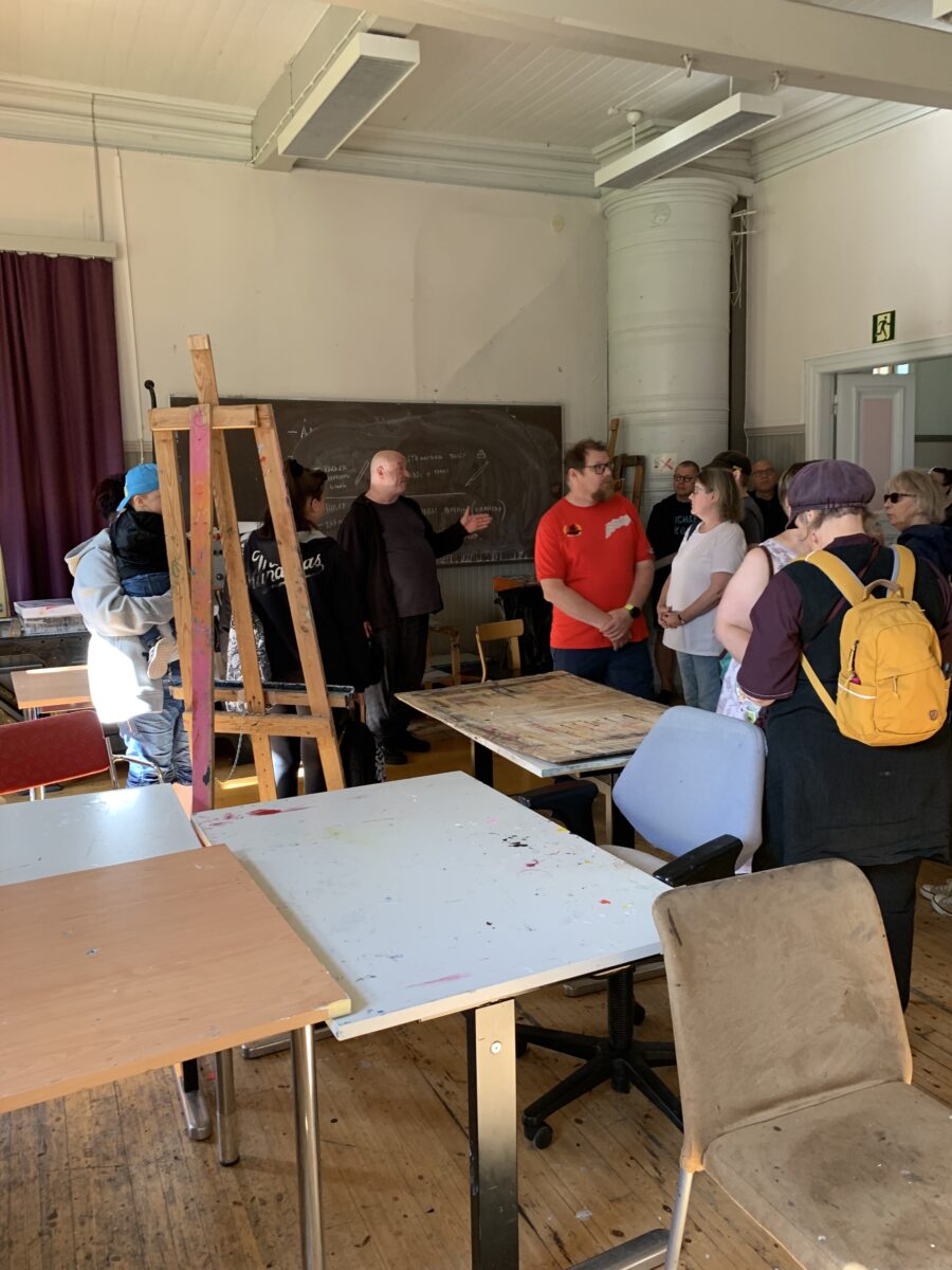 Mies esittelee luokkatilaa ihmisryhmälle.