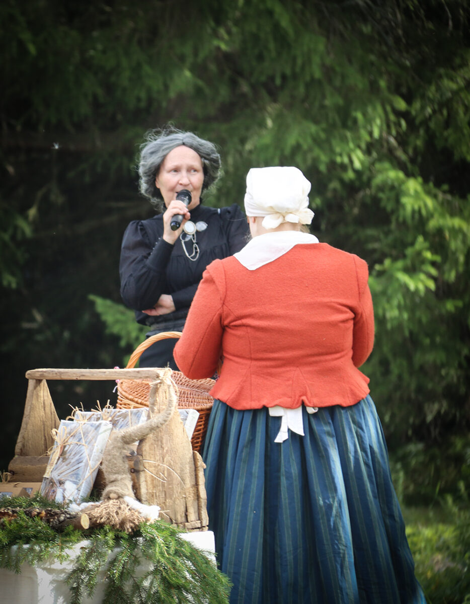 Katri Tuoriksi pukeutunut henkilö puhuu mikrofoniin.