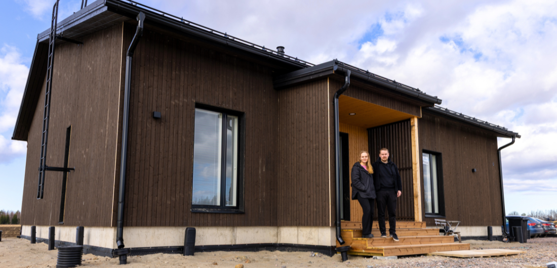 Iida ja Ilari Kinnunen seisovat oman kotinsa eturappusilla aurinkoisena päivänä.