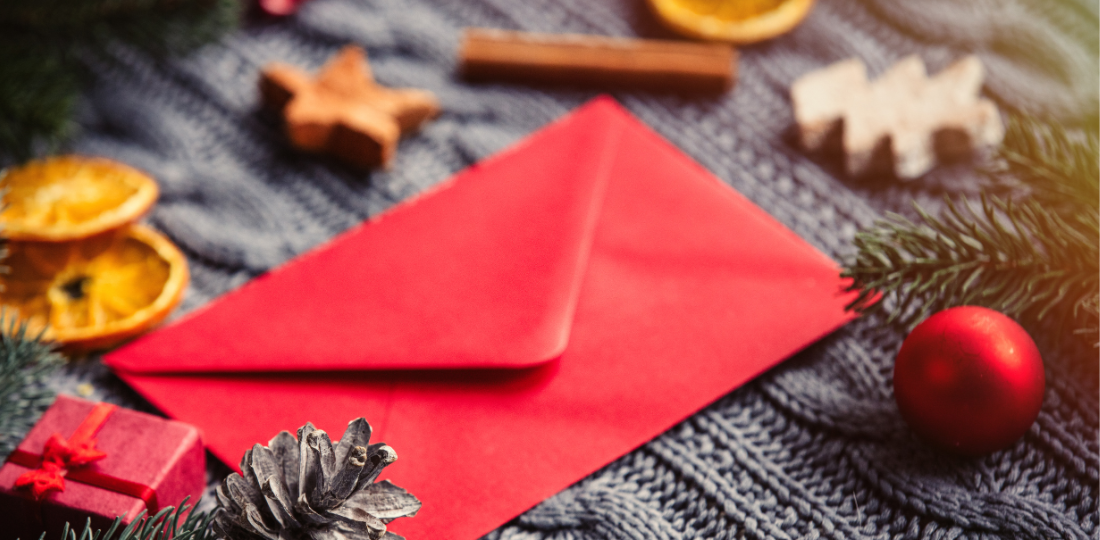 Punainen kirjekuori joulukoristeiden keskellä.