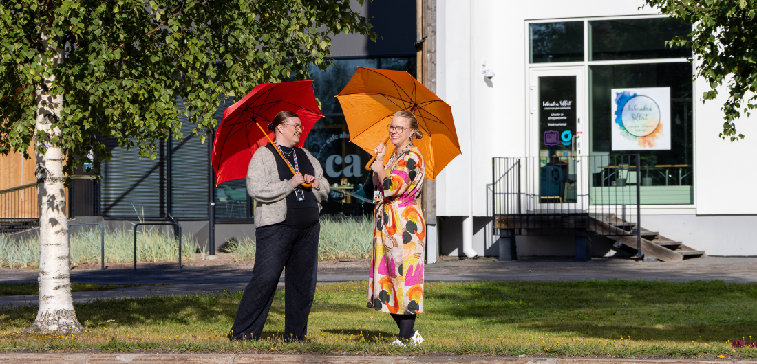 Hanna Ikonen ja Kaisa Salmu Lakeustalon edustalla sateenvarjot käsissään.