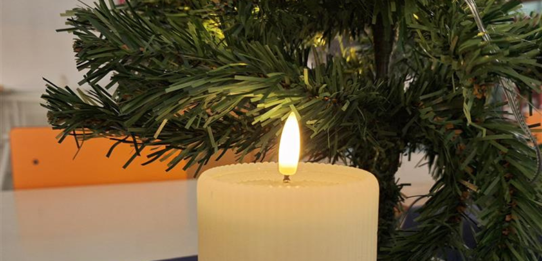 Led-kynttilä pöydällä tekokuusen edessä.