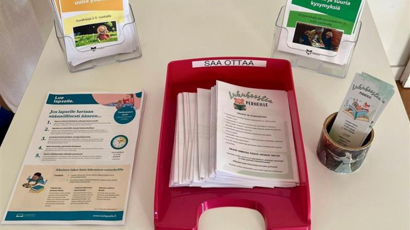 Kirjaston pöydällä monisteita, joissa on tarjolla lukuvinkkejä.