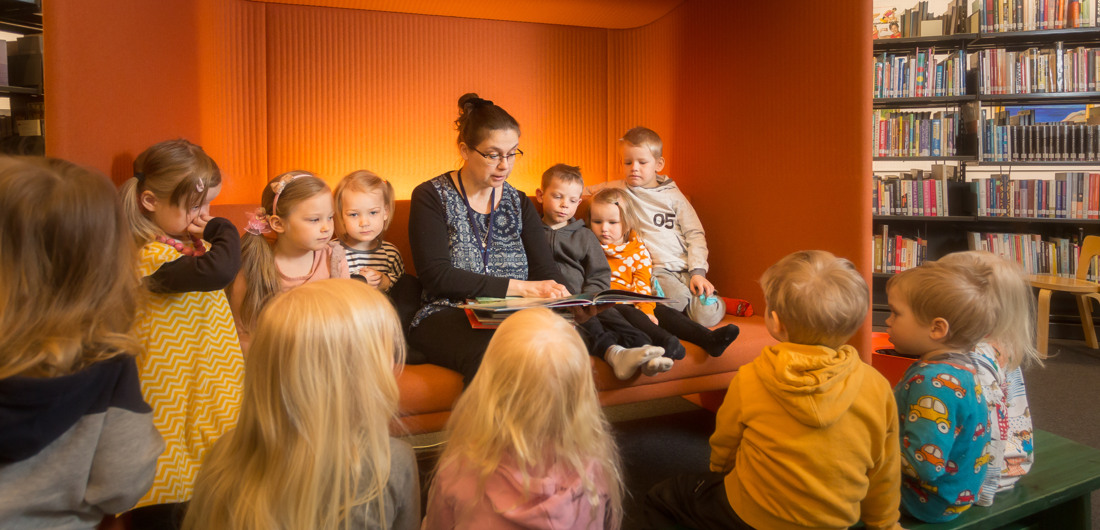 Kirjaston työntekijä lukee lapsille kirjaa.