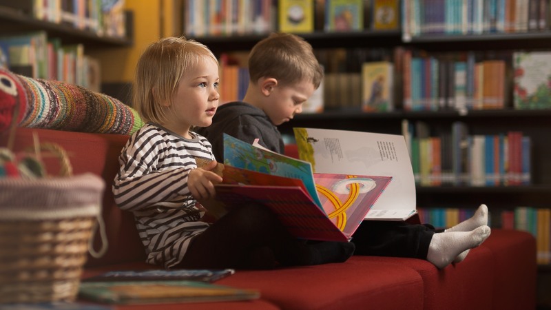Lapset lukevat kirjaa kirjastolla.
