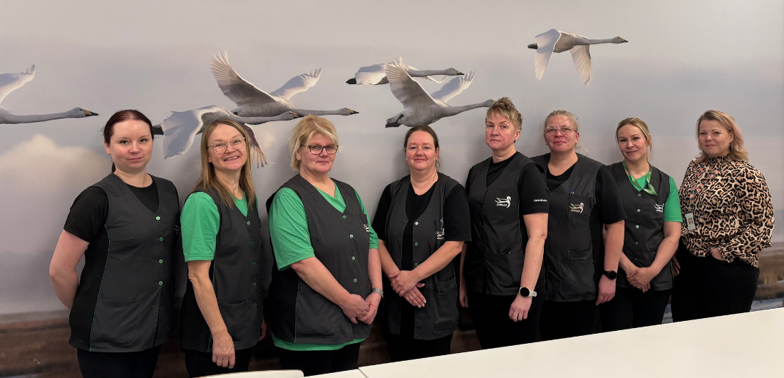 Laitoshuoltajat Linnukun koulun ruokasalissa joutsen-seinän edessä.