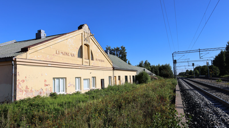 Valokuvassa Limingan osuusmeijerin seinä ja junaraiteet.