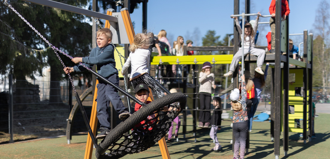 Lapset leikkivät koulun pihalla kiipeilytelineiden luona.