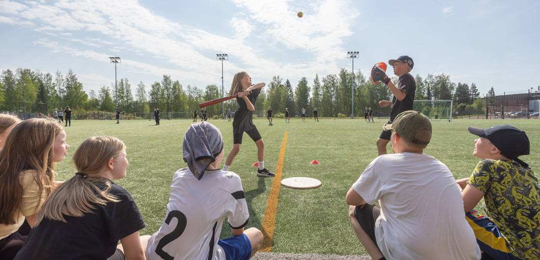 Lapset pelaavat pesäpalloa.