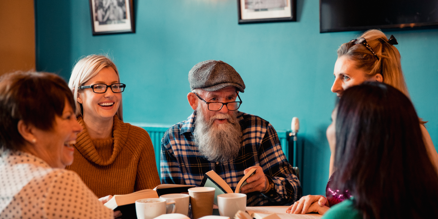 Ryhmä eri ikäisiä ihmisiä kokoontuneena pöydän ääreen.
