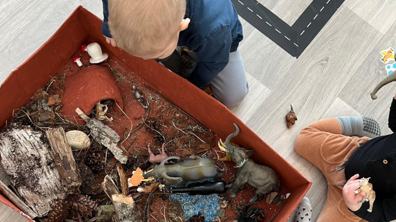 Lapset ihmettelevät sisään tuotuja kaarnaa, puuta ja käpyjä. 