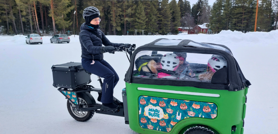 Lapset muksubussin kyydissä talvisessa maisemassa.