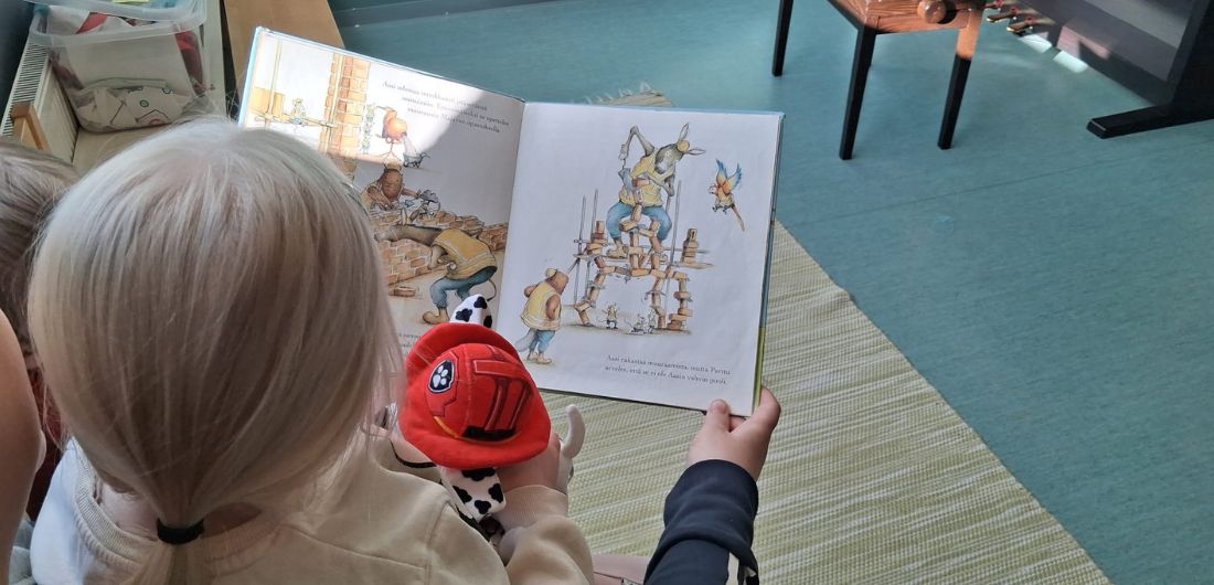 Kuvassa lapsi katselemassa satukirjaa.