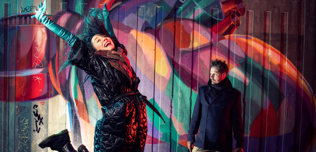 Nainen ja mies värikkään graffitiseinän edessä