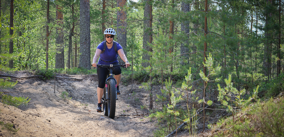 Pyöräilijä pyöräilemässä maastossa kesällä.
