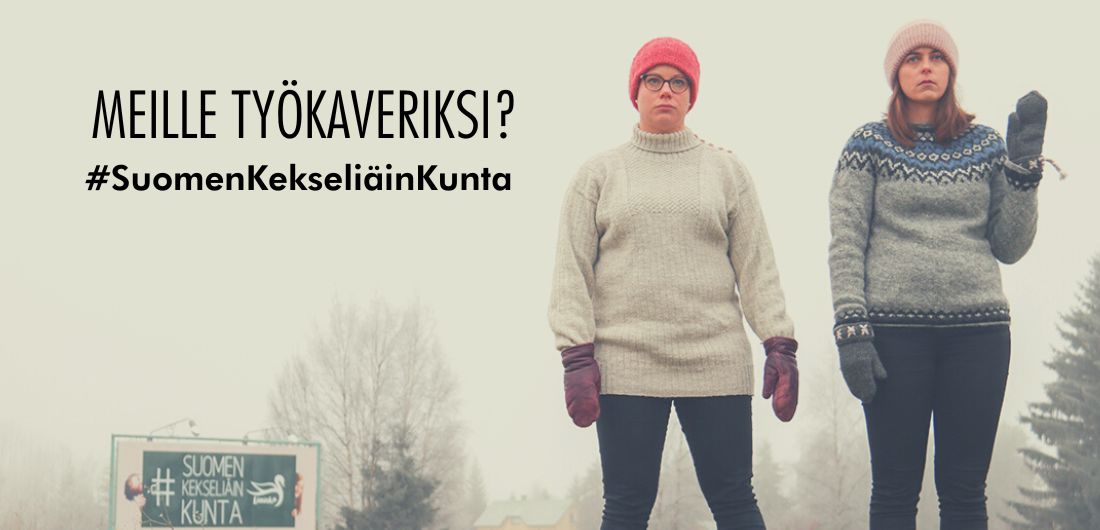 Kaksi naista seisoo Suomen kekseliäin kunta -kyltin edessä villapaidat päällä.