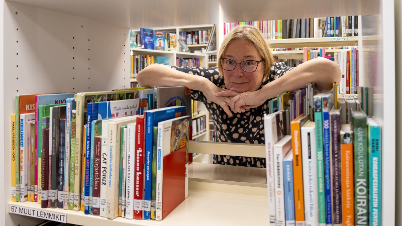 Sari Kalliokangas kirjahyllyn välissä.