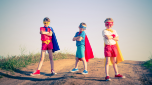 Lapset supersankariasuissa poseeraa tiellä