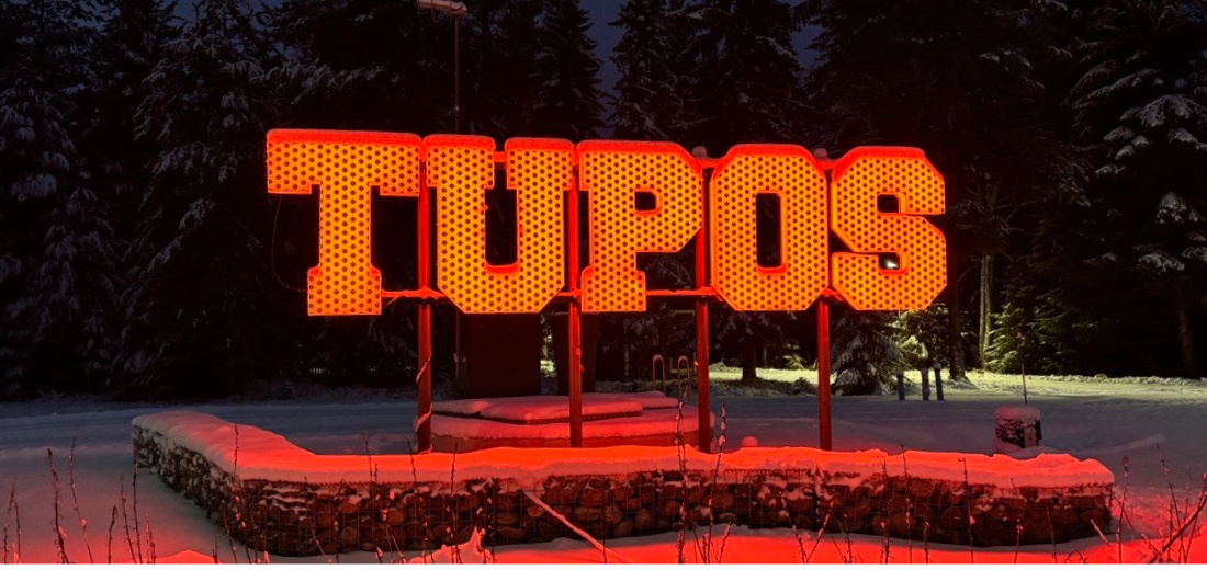 Tupos-kyltti loistaa oranssina pimeässä, talvisessa säässä.
