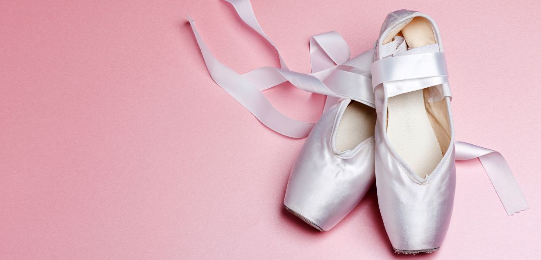 Balettitossut vaaleanpunaisella taustalla.