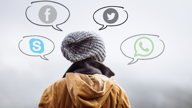 Nuori seisoo pipopäässä selin kameraan ja puhekupliin on laitettu somekanavien ja pikaviestimien kuvakkeita.