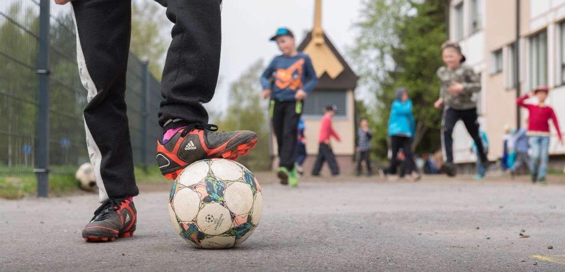 Koululaiset pelaavat jalkapalloa.