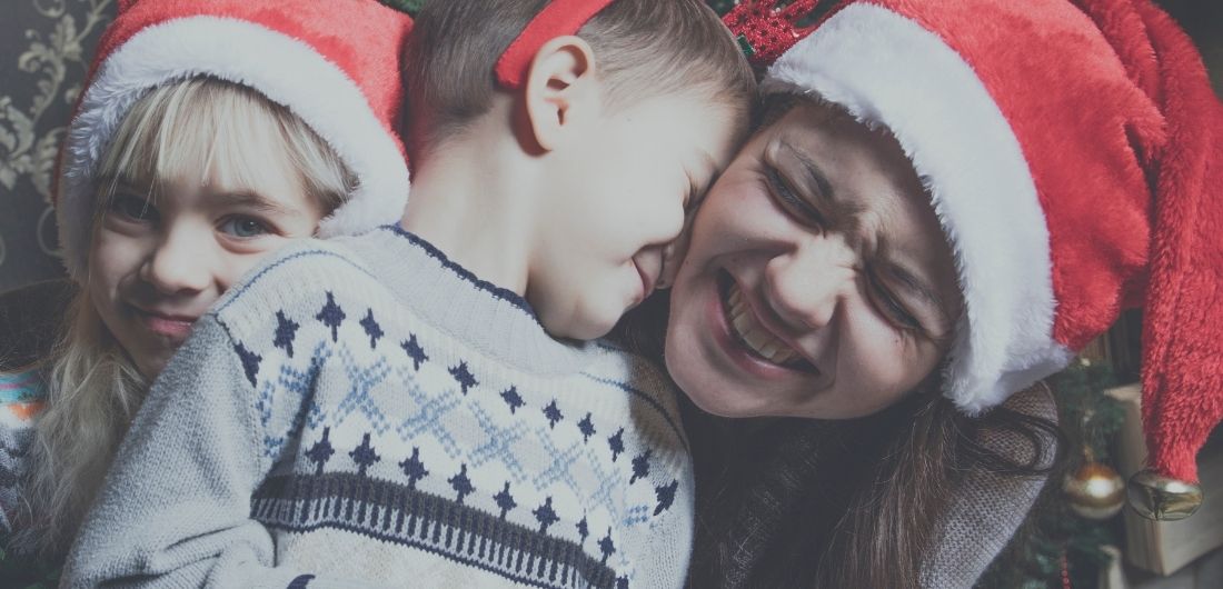 Perhe joulutunnelmissa tonttulakit päässä.