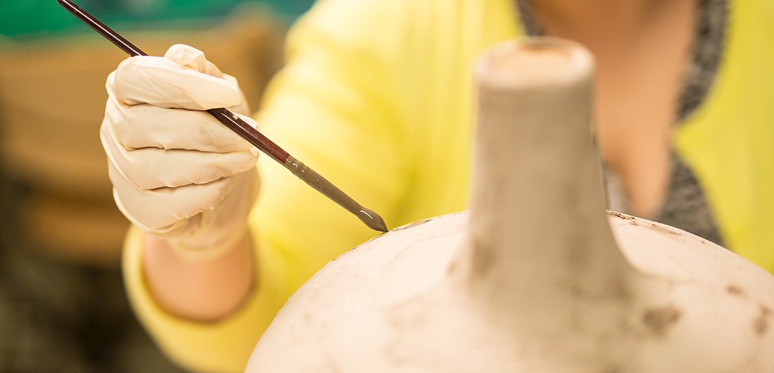 Keramiikkatyötä maalataan siveltimellä.