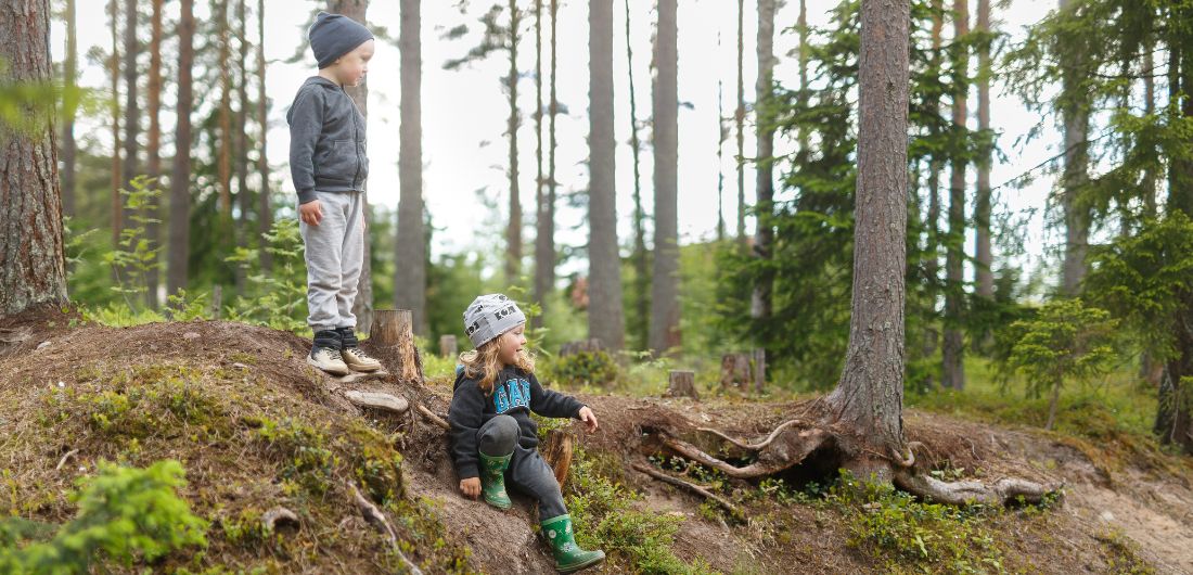 Kaksi lasta leikkimässä metsässä.