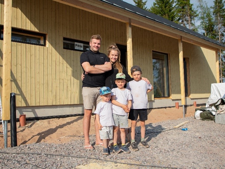 Kotirantaan rakentava perhe talonsa edustalla.
