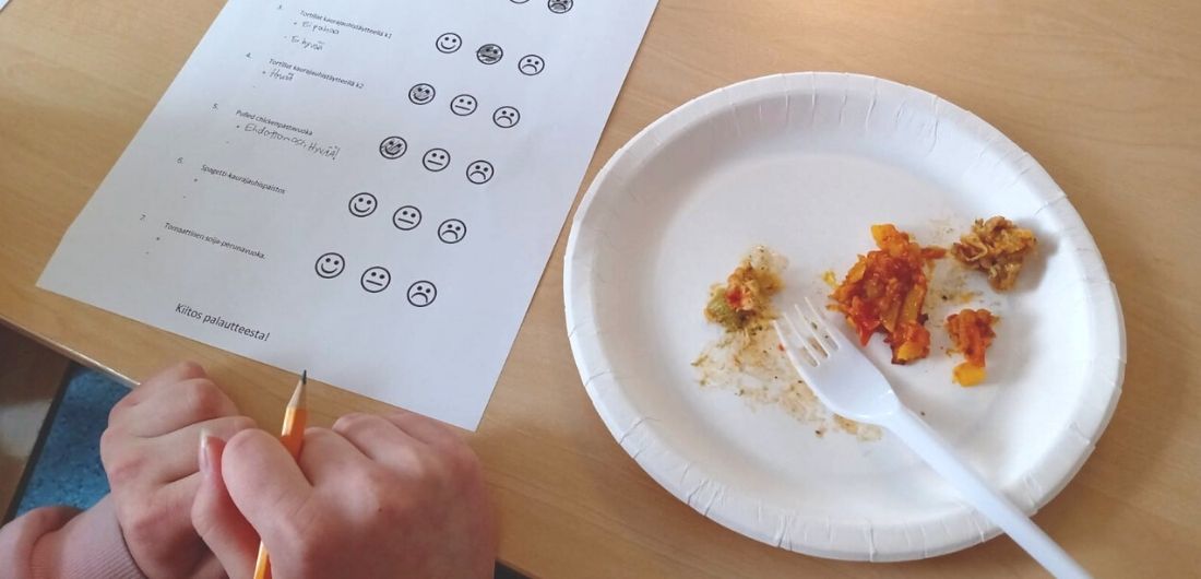 Maisteltava kouluruoka pöydällä, vieressä arviointilomake.