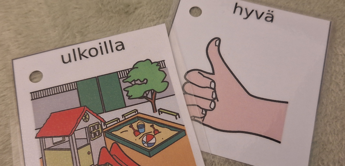 Kuvakortit maton päällä. Ulkona -kuvakortissa näkyy piirretty ulkomaisema ja hyvä -kuvakortissa peukkua näyttävä käsi.
