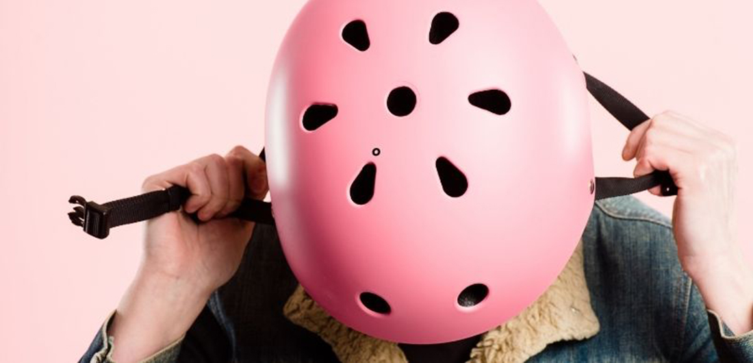 Vaaleanpunaista kypärää laitetaan päähän.