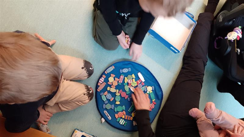 Lautapeli, jota pelaamassa aikuinen ja lapsia.