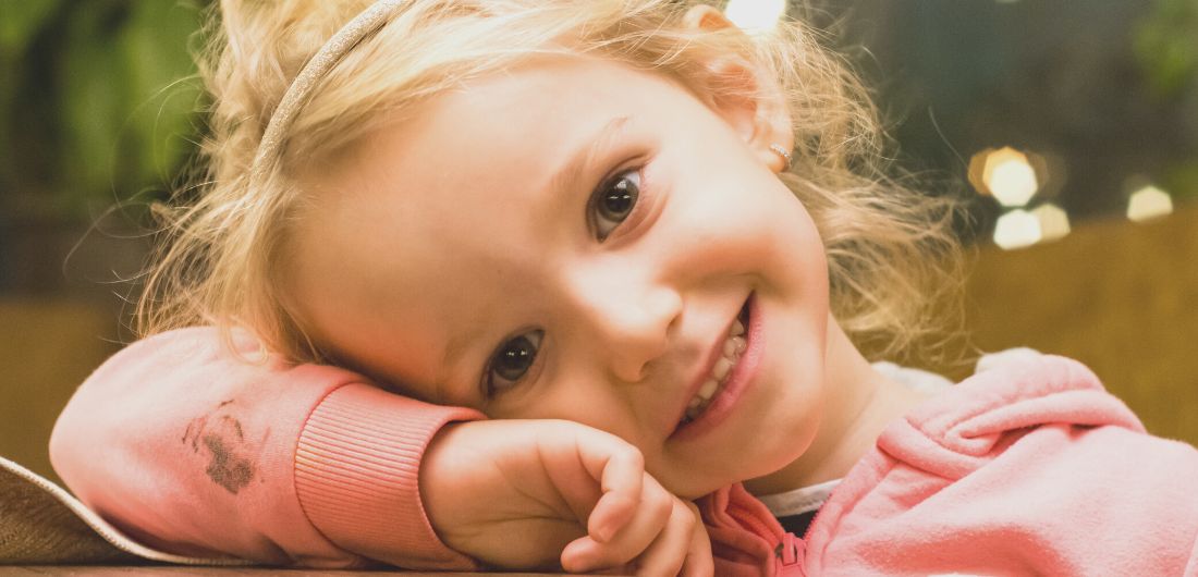 Lapsi hymyilee ja nojaa käsivarteensa.