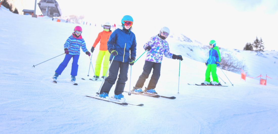 Nuoret laskettelevat värikkäissä ulkoiluasuissaan.