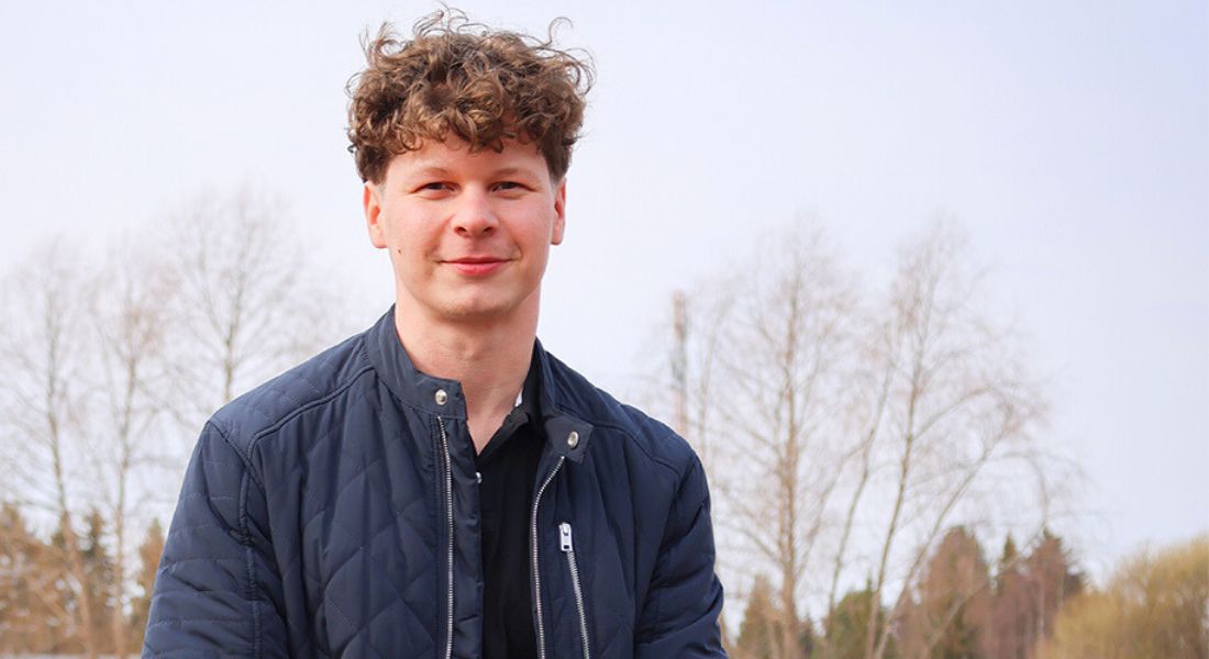 Mies istuu ulkona syyssäässä muurin päällä.