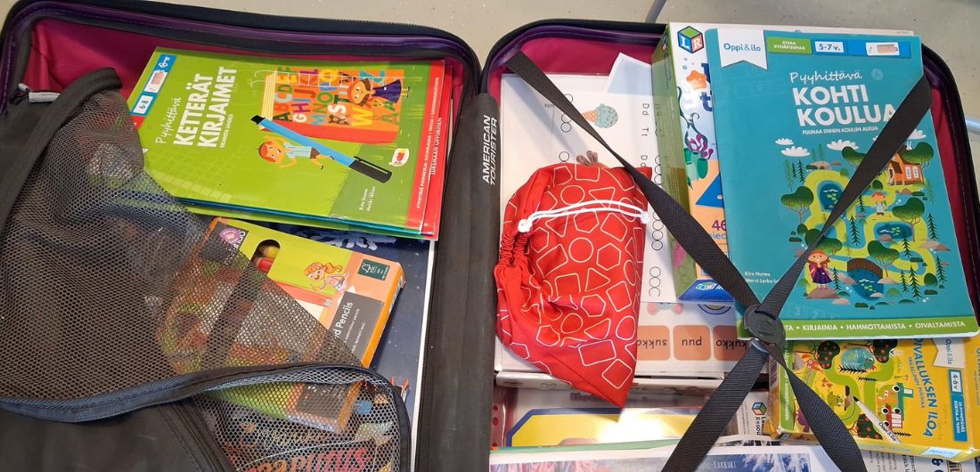 Varhaiskasvatuksen erityisopettajan työvälineitä, kuten kirjoja, matkalaukun sisällä.