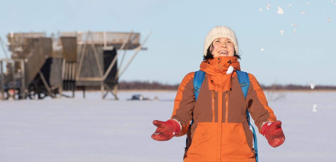 Nainen heittää lunta ilmaan Virkkulan lintutornin edessä.