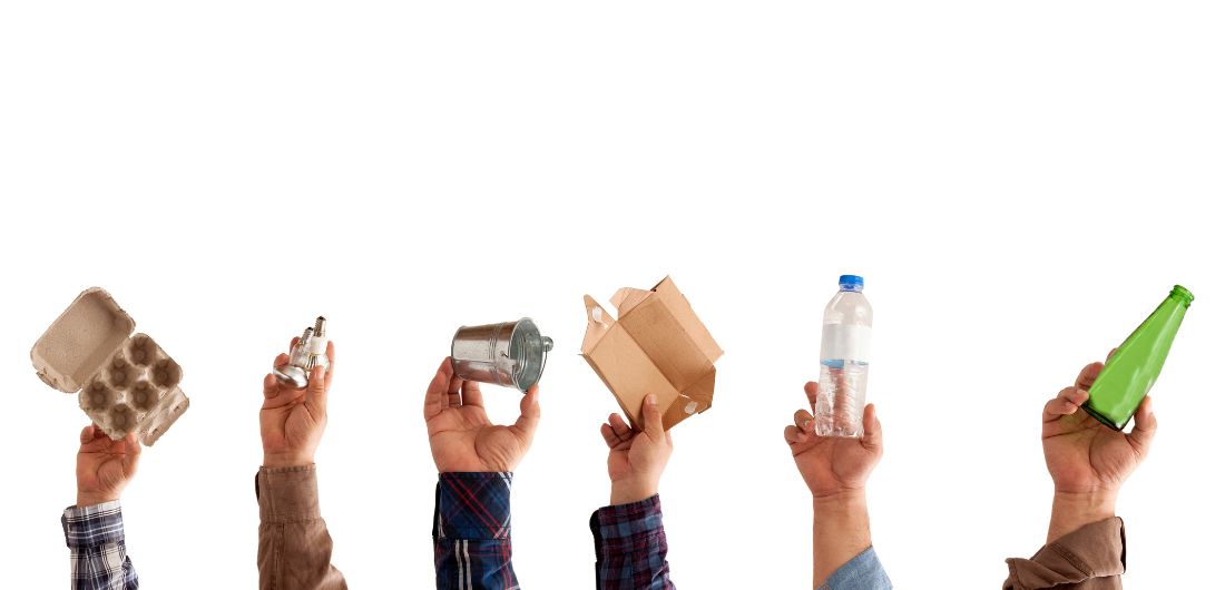 Kädet pitelevät kierrätettäviä jätteitä.