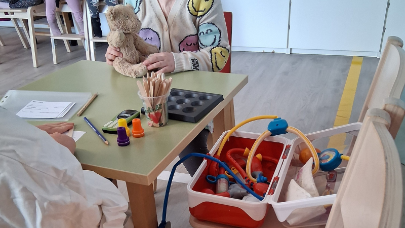 Lapset leikkivät neuvolaa nallelelun kanssa.