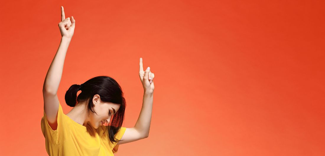 Nuori nainen tuulettaa keltaisessa teepaidassa.