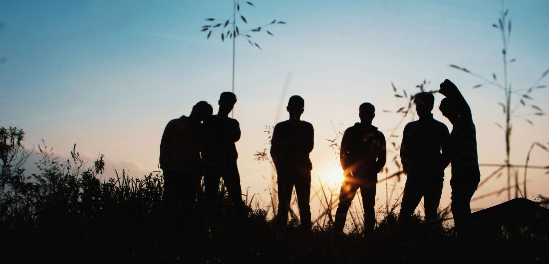 Nuoret seisovat auringonlaskussa